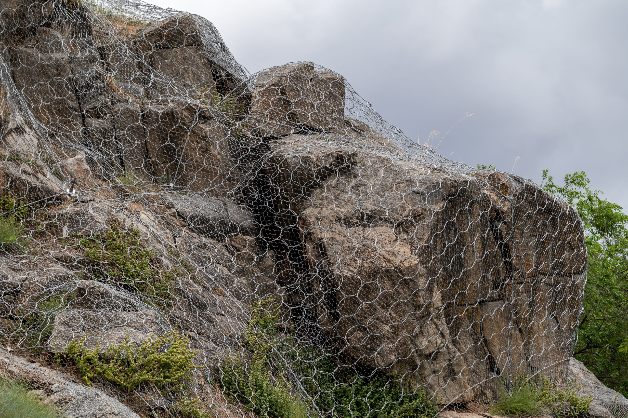 Rock slope covered with wire mesh for rockfall protection.